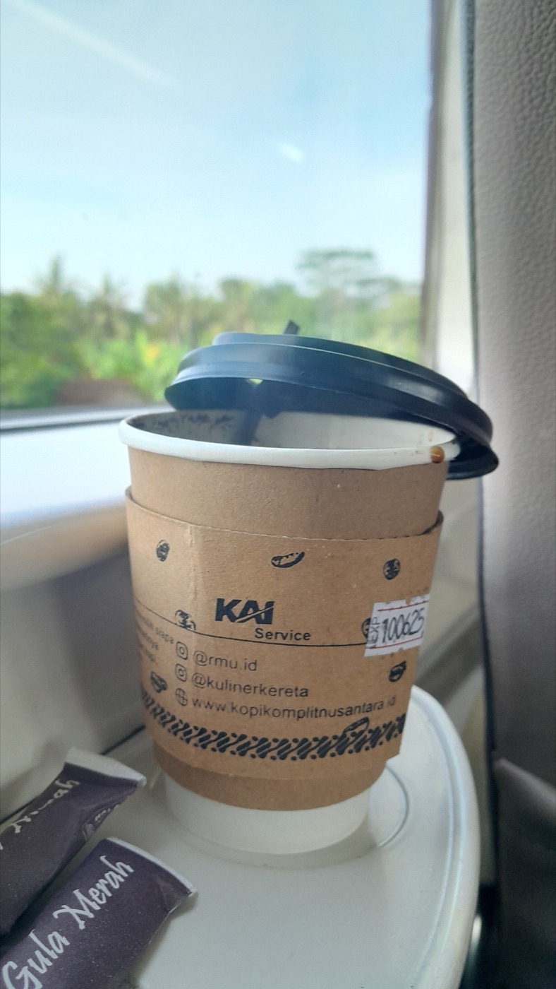 A cup of coffee beside a train window.
