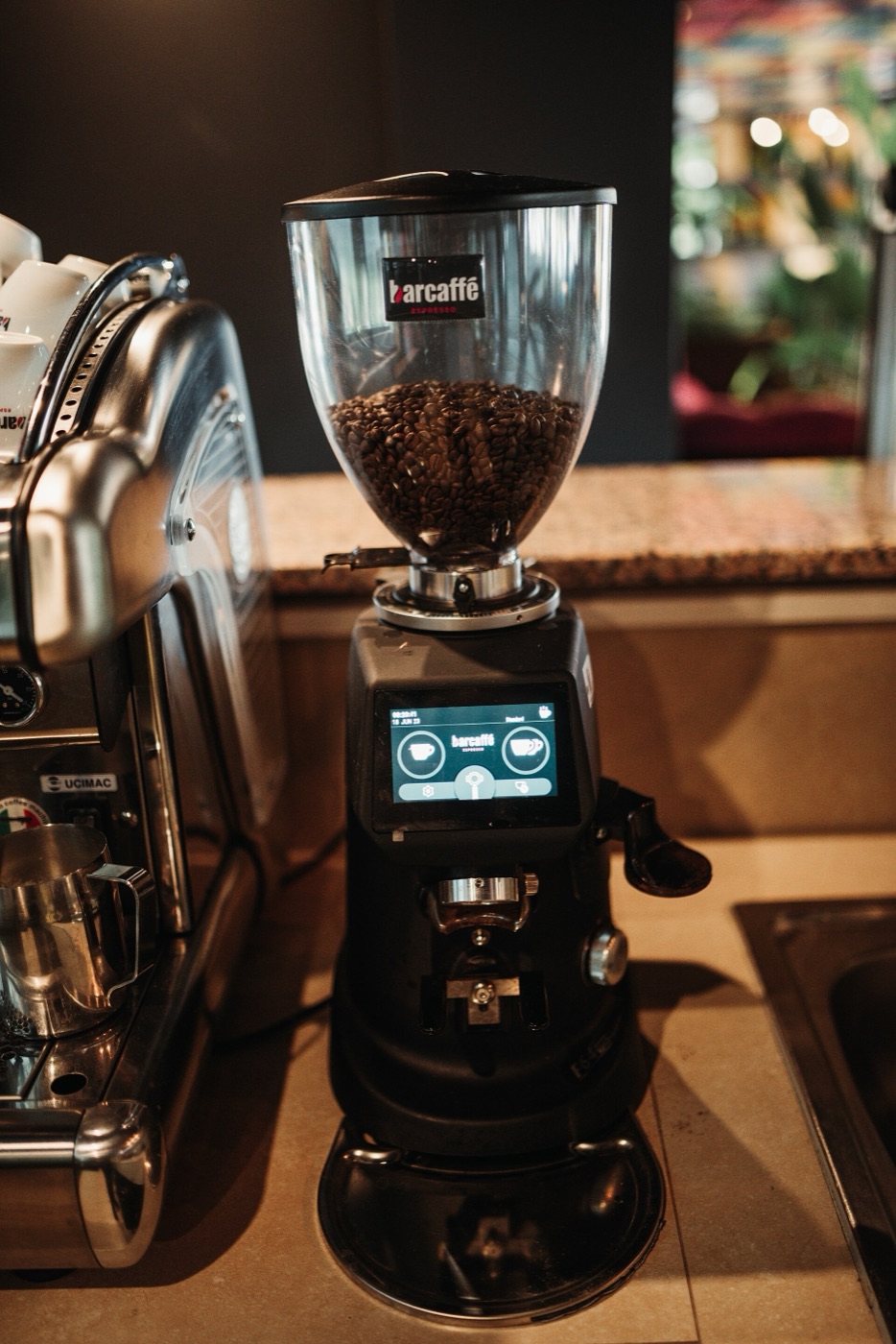 A coffee grinder and beans arranged in a cafe setting.