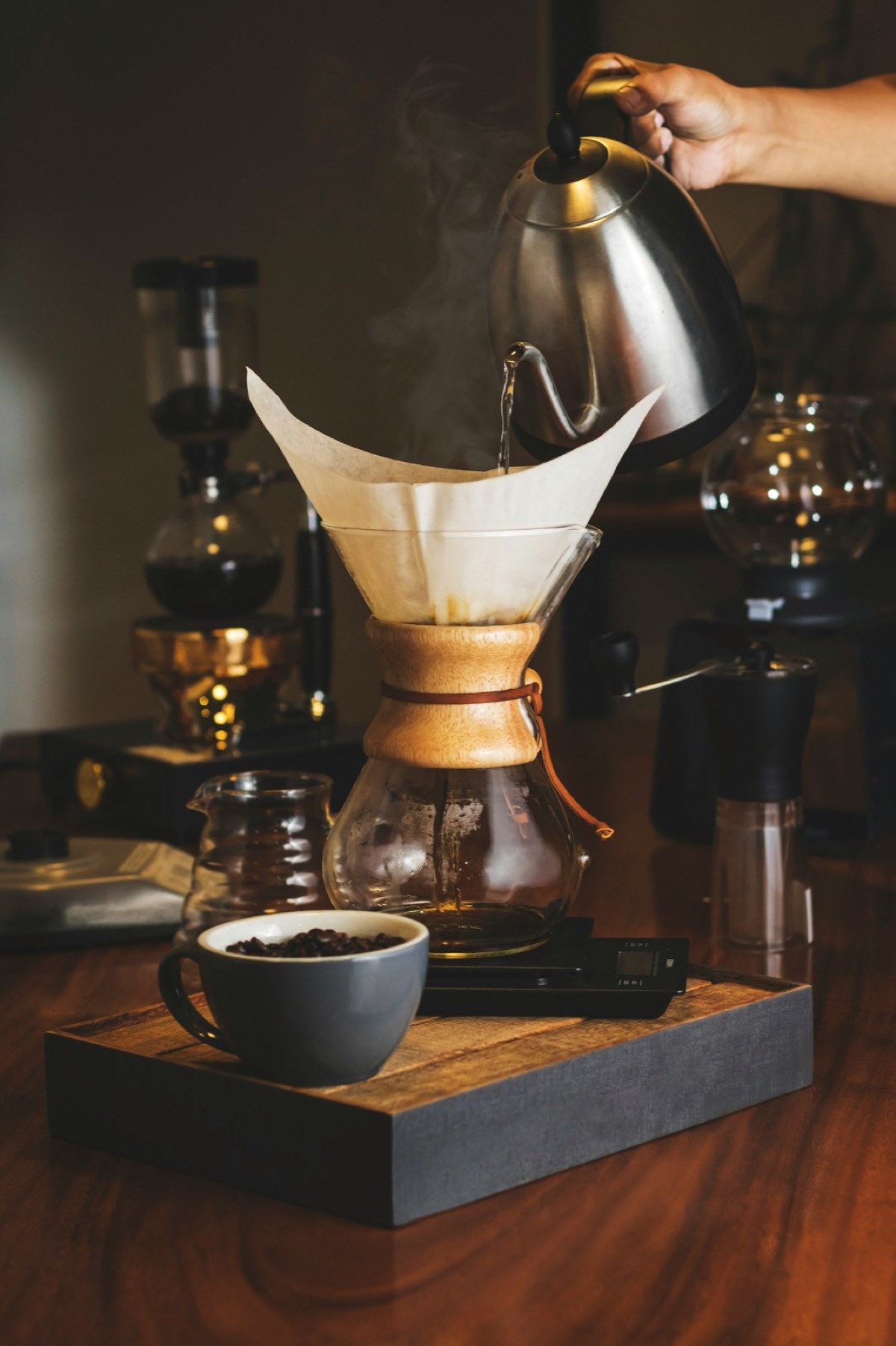 Water being poured into a clear glass vessel for coffee brewing.